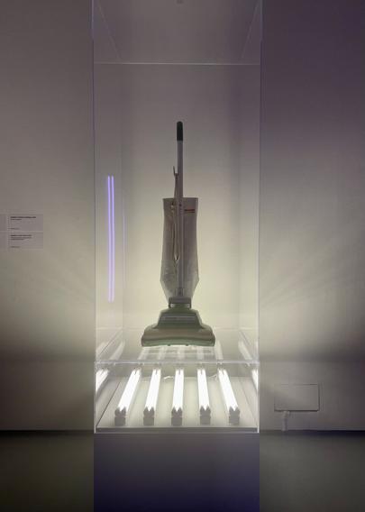 Noah Davies’ Imitation of a Jeff Koons at The Barbican. This is a retro hoover in a perspective box underlit by five neon strip lights.