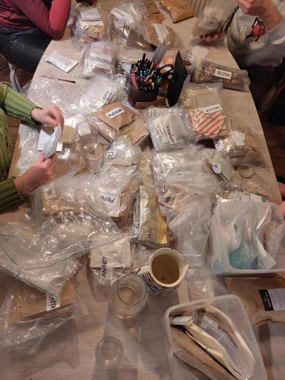 Table littered with seed bags and hands putting seed in bags