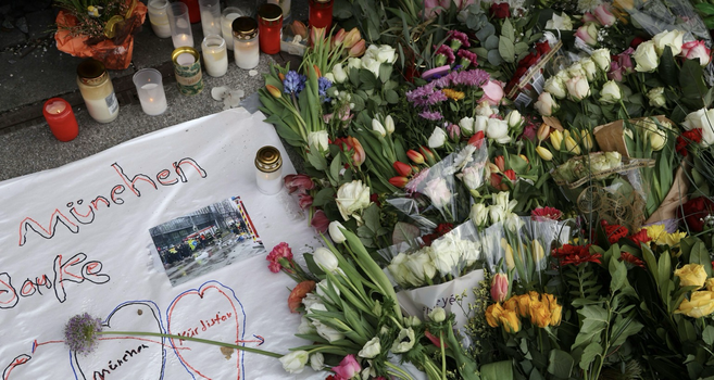 Kerzen und viele Blumen liegen auf dem Boden um den Opfern des Anschlags in München zu gedenken.