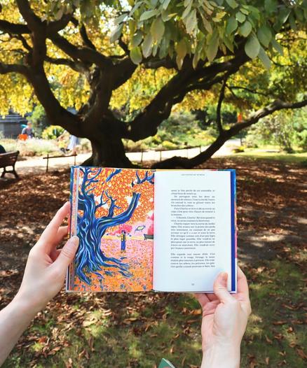 After getting back on her feet, Charlie stands before the weeping hornbeam, taking one last look at the cep. She waves goodbye to it, as well as to the underground fauna and flora. Around her, the grass is bathed in pink and orange hues, and the tree's roots extend deep into the soil, echoing the subterranean network she has just left behind.