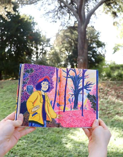 Charlie appears in the foreground, facing us with a smile on her lips. She walks along a path lined with trees in autumnal colors, bathed in shades of pink, yellow, and blue. Her yellow coat stands out against the landscape, while in the background, the silhouettes of other visitors can be seen. Further in the distance, the imposing Cedar of Lebanon from the Jardin des Plantes is visible in blue, mirroring its presence in the photograph behind the book.