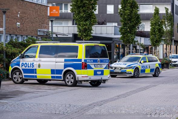 Two police cars parked on a street outside a pharmacy.