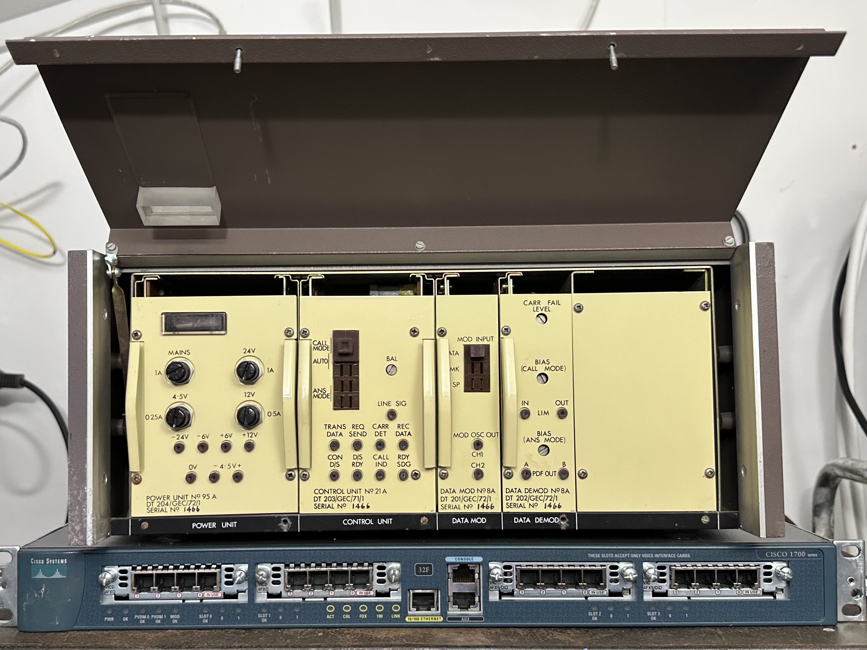 Lifting the front panel reveals four removable modules that slide into the chassis.  They’re light straw coloured (a yellowish cream) and from left to right are labelled power supply, control unit, modulator and demodulator.  There are various indicators, controls, and test points available