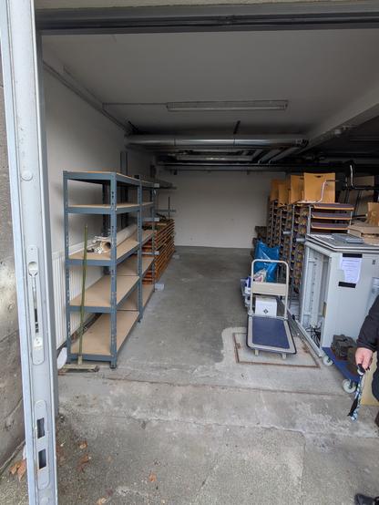 Eine leere Garagenhälfte. Links noch leere Regale, in der Mitte viel leere Fläche, rechts Zeug von anderen Leuten.