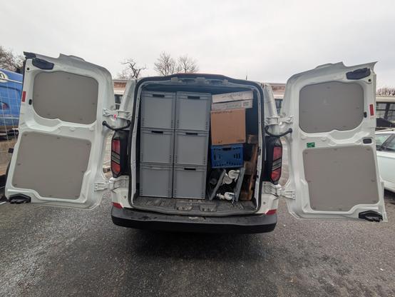 Ein randvoll gefüllter Transporter von hinten mit geöffneten Flügeltüren