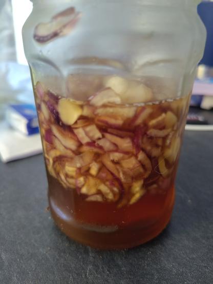 Foto. Glas mit Honig Zwiebeln und Knoblauch gefüllt. Ansicht von der Seite