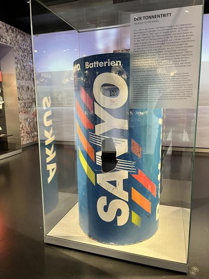 Die echte Tonne von Klinsmanns Tonnentritt. 


DER TONNENTRITT
THE BOOT TO THE BARREL
Der „Tritt in die Tonne" hat längst Einzug in den allgemeinen
Sprachgebrauch gehalten. Zu verdanken ist dies Jürgen Klinsmann,
der von 1995 bis 1997 beim FC Bayer spielte. Als Trainer
Giovanni Trapattoni den Nationalstürmer und Weltmeister am
10. Mai 1997 im Olympiastadion in der 80. Minute des Bundes-
ligaspiels gegen den SC Freiburg (0:0) aus- und den Amateur
Carsten Lakies eingewechselt hatte, trat Klinsmann wutentbrannt
mit dem rechten Fuß in eine am. Spielfeldrand aufgestellte
Werbe-Tonne. Zurück blieb ein Loch, das dem Batterie-Hersteller
zu unverhoffter Aufmerksamkeit und erhöhten Umsätzen
verhalf. Zwei Jahre später - bei seinem Abschiedsspiel 1999 im
Stuttgarter Neckarstadion - bewies Klinsmann dann Selbstironie:
Mit einem sanften Tritt gegen eine ähnliche Werbe-Batterie
setzte er ein Feuerwerk in Gang. bevor die Original-Tonne
schließlich ihren Weg ins FC Bayern Museum fand, war sie bei
Ausstellungen und Werbeaktionen zu sehen und brachte Geld
für wohltätige Zwecke ein.