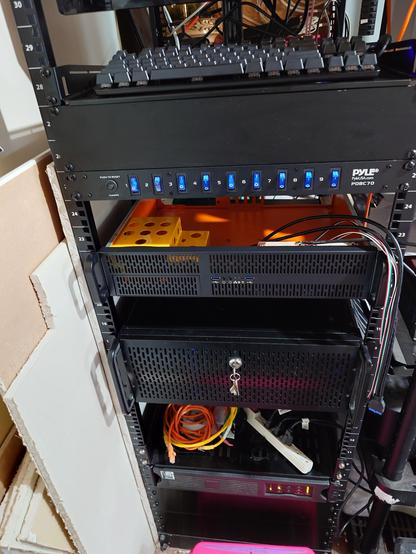 View of a rack, messy, missing blanking panels. 2U server opened up to show orange/yellow interior