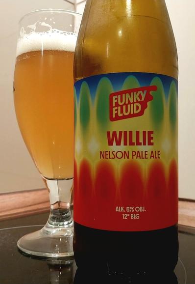 A glass of Funky Fluid beer standing next to a bottle with colourful design.
