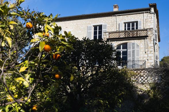 Orangenbäumchen vor alter Villa, blauer Himmeleinsamer Leuchturm im Meer am Ende einer Mole, gesehen durch eine Mauenische einer Festung
