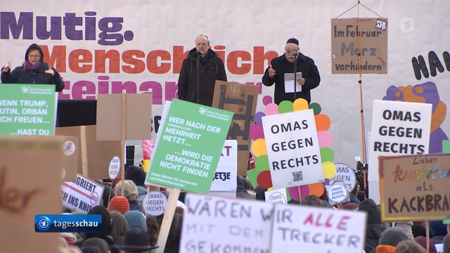Ein Sreenshot aus der tagesschau mit Blick Richtung Bühne. Auf der Bühne sind zwei Redner zu sehen, Im Vordergrund viele Schilder , u.a. von den Omas gegen Rechts.
Oben rechts im Bild ist die Rückseite meines NoNo Schildes zu sehen, auf der steht: Im Februar Merz verhindern.