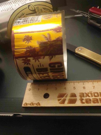 Bande d'alu de 43mm de large découpée dans une canette, avec couteau suisse, couteau de Maniago fox vulpis simple lame et règle en bois à côté