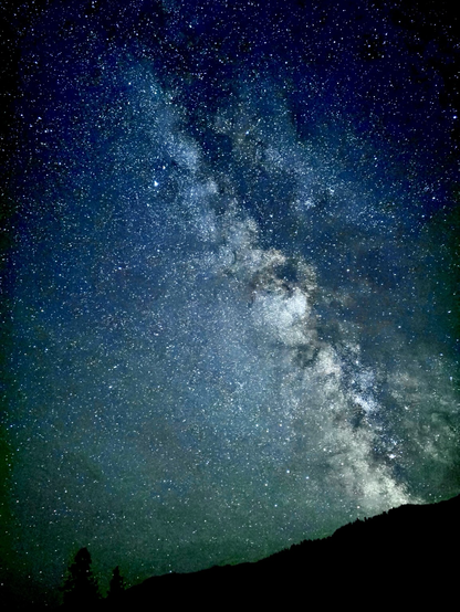 The Milky Way galaxy over the silhouette of a forested hillside in rural Idaho.