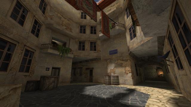 In this picture you can see the courtyard and two alleys. One left and one right. The left one is the alley, with the illuminated lamp from the previous photo series. Further up you can see balconies. A rope is attached to one of them, on which carpets hang. Furthermore, you can see wooden boxes and barrels again. This is on the map de_torn in the game Counter-Strike 1.6.