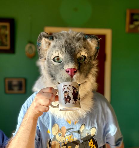 Snow leopard fursuit having a coffee in the sunlight.