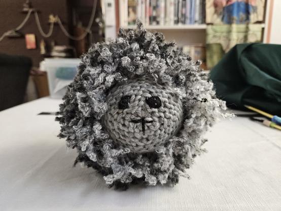Knitted toy sheep, made mainly on a 24-peg knitting loom, and finished on 6mm double-pointed needles. Yarn: Ice Yarns Oh La La scarf yarn (grey shades) and Lincraft All Sorts Acrylic single-strand bulky (Grey). The eyes and mouth were embroidered with BWM Luxury 8-Ply Merino (Black). Stuffed with polyfill.