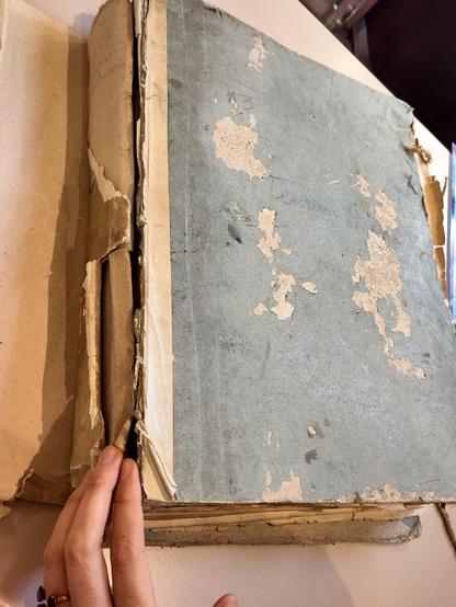 Photo d'un vieux registre d'archives. La couverture en carton est très abîmée