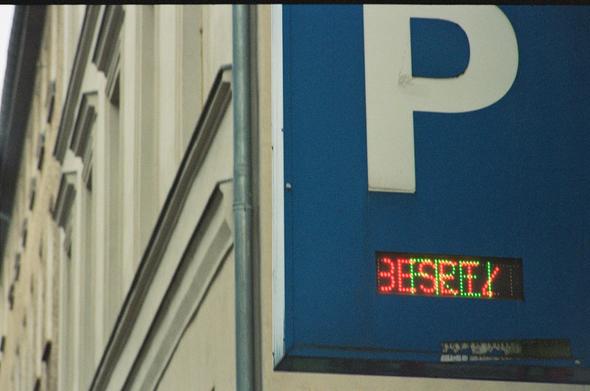A blue parking sign where the status LED shows both states: free and occupied. In the background are beige old housesfronts.

Shot on Lomography Color Negative ISO 800