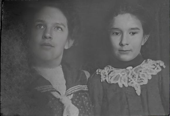 Black and white photograph of a woman in a sailor blouse next to a young women in a dress with a white lace collar.