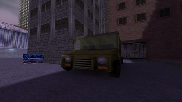 In this picture you can see a green car. In the background are buildings. Directly behind the car is a ladder on the building, and to the right of the ladder is a gate. On the left edge of the picture you can see a warehouse made of sheet metal and stone bricks. This is on the map cs_assault in the game Counter-Strike 1.6.