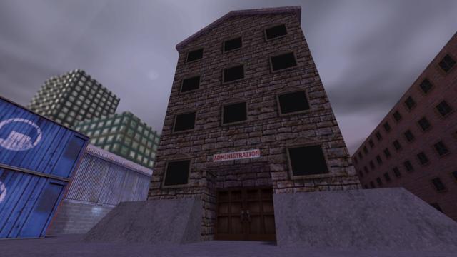 In this picture you can see a building with a lot of windows. This is behind the position of the two pictures before. Above the entrance of this building is a sign with the word Administration in red. On the left you can see two blue Stacked containers, with a white Black Mesa logo in the middle, as well as the warehouse made of sheets and stone bricks and behind them you can see two high-rise buildings. On the right you can see a building made of red bricks and there are many windows installed here. This is on the map cs_assault in the game Counter-Strike 1.6.