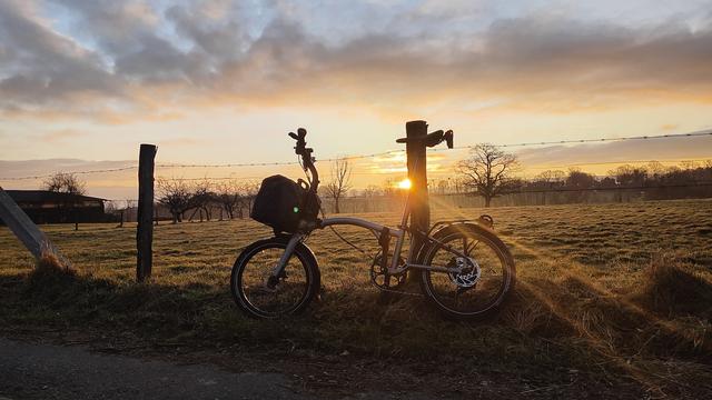 A Brompton G Line bicycle with the sound rising above the horizon behind it.