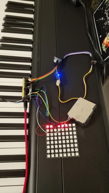 Auf einem Klavier liegt ein Mikrocontroller, an dem mehrere Sensoren und eine LED Matrix angeschlossen sind.