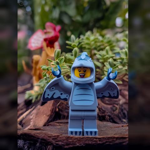 Lego figure dressed as a pterodactyl with a raptor hiding in bush behind ready to strike