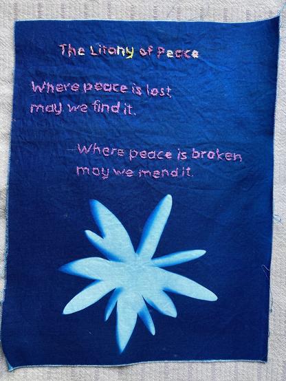 An embroidered cyanotype with the following words in purple:
"The Litany of Peace. Where peace is lost, may we find it. Where peace is broken may we mend it." Below the words is a cyanotype of a flower.