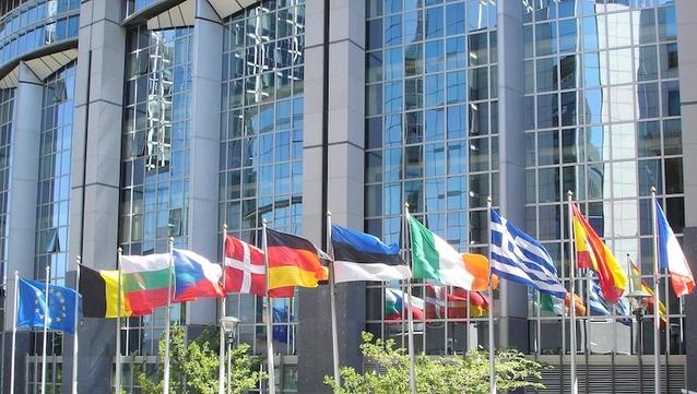 Flagge der EU und mehrerer Mitgliedsländer vor einem Gebäude