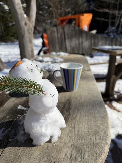 Kleiner Schneemann auf dem Picknicktisch im Wald
