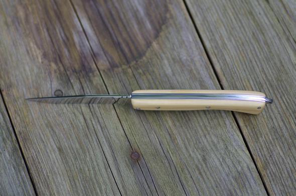 Un couteau de poche avec un manche en buis clair, vu du dessus