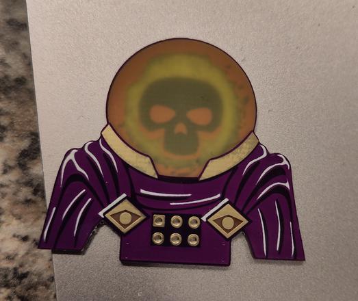mysterio badge with no backlight shows copper colored eyes and jaw with dark skull