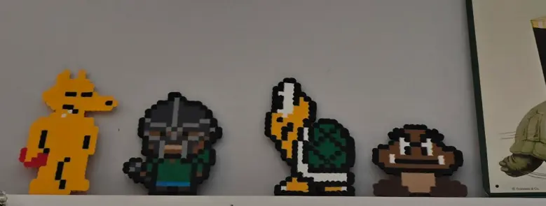 The image shows four pixelated figures and a portion of a sign. From left to right, the pixelated figures are Jake the Dog from Adventure Time, a pixelated Viking, a pixelated Koopa Troopa, and a pixelated Goomba. The sign to the right is a turtle.