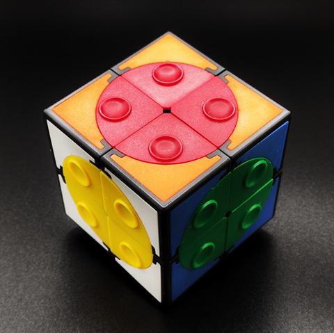 Foto del mismo cubo, ahora en una perspectiva más tradicional que nos permite ver tres caras (blanca, anranja y verde) con sus tres círculos (los colores "invertidos", amarillo, rojo y azul).