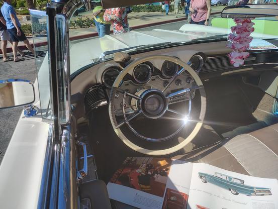 The front seat of this 1960 Lincoln convertible and its instrument panel, every bit is color-coordinated in tan and cream to match the car's exterior.  There are four round binnacles for the instruments, a filigreed chrome decoration extends on either side of the binnacles beneath the dashboard and the autronic eye which automated high beams, a highly regarded luxury feature of cars of the 50s and early 60s.