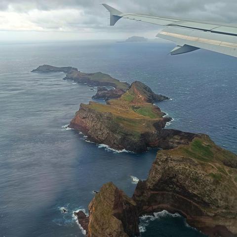 Small islands of Madeira in a grey blue sea, seen from the plane