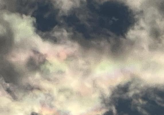 Looking at subtle pink and green highlights in remnants in relatively low cumulus clouds moving fast with strong cold winds from the north east. The coloring is from light diffraction though ice crystals in a similar manner to how a rainbow forms.