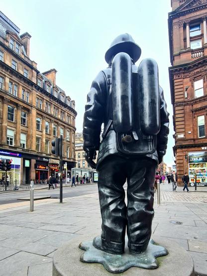 A statue of a firefighter in full beathing apparatus on a Glasgow street.