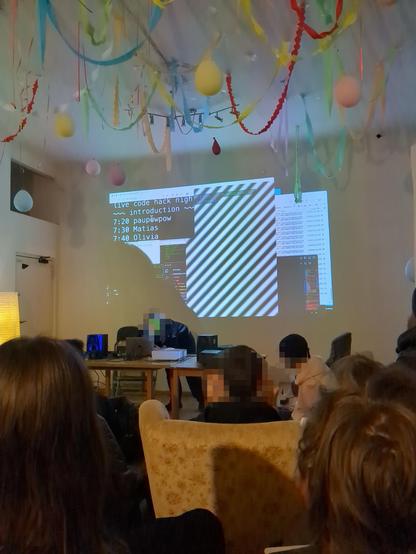 A photo of a room full of people looking at a projection of diagonal lines