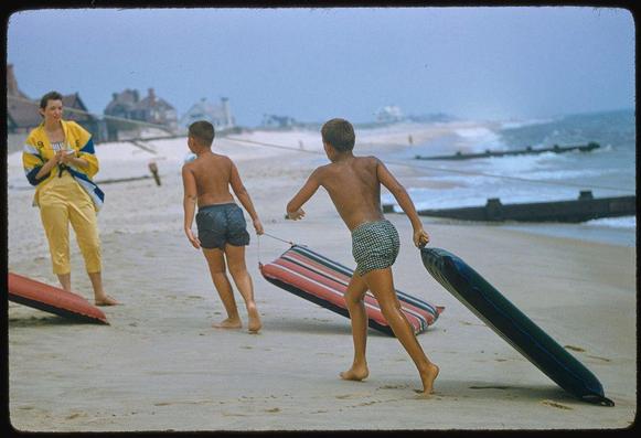 Caption: A family walking on a beach in the 1950s with surfboards and rafts.
This photograph captures a typical day at The Hamptons, Long Island during the mid-20th century as seen through the lens of renowned American photographer Toni Frissell for Sports Illustrated magazine.
Date: August