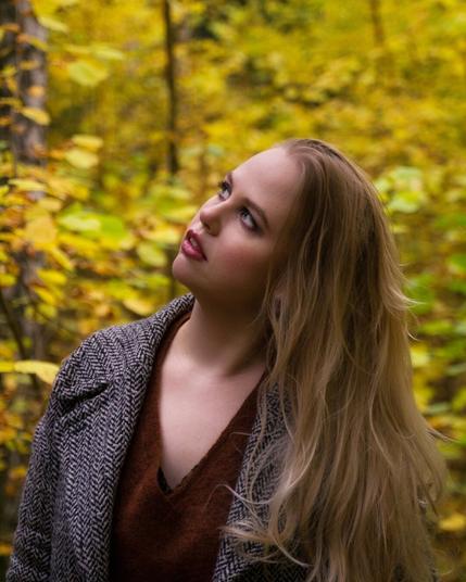 Portrait of a blonde woman in an autumn forest with yellow leaves