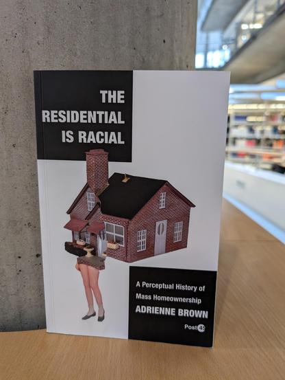 The book "The Residential is Racial" by adrienne brown in the reading room of SUB Göttingen, leaning against a stone pillar