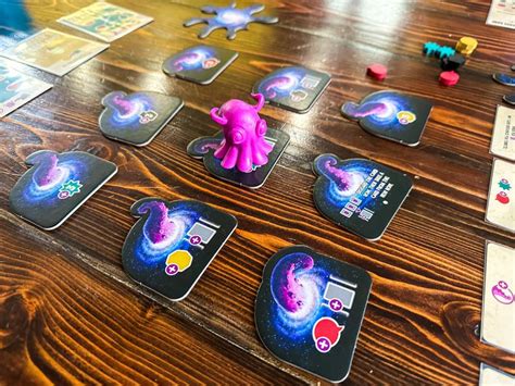 Part of the game showing nine action tiles in a 3 by3, with the cosmostopus figure sitting on the middle one.