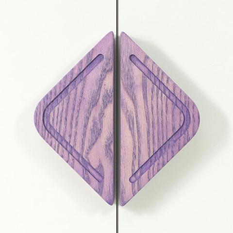 Two diamond-shaped handles made of wood with a purple hue, featuring a carved pattern that follows the shape of the handles. The handles are placed symmetrically, suggesting that they are on two adjacent doors or drawers.