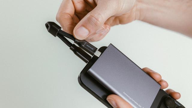 Eine Hand vor weißem Hintergrund verbindet ein Nomad ChargeKey zwischen einem iPhone und einer Powerbank. Foto (c) Nomad.