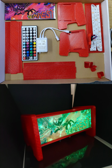 top half of image shows a cadboard box, in it is a dissassembled kit of red 3d printed plastic parts, a colourful remote control, an electronic box of sorts aand a panel with 3 strips of LED stuck to it. 
in the top left corner of box, is a panel with the marquee graphics of an arcade game tempest.
the bottom half of the image shos all the parts assembled into a mini box like light similar to the top of an arcade cabinet, with the tempest game logo backlight from within.