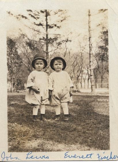 Full image of the original scanned photo...1920 photo of two toddlers wearing rounded caps and big, puffy playclothes. Their tall white socks are easily visible above their old-fashioned playshoes. In the background, there are lots of trees, with few leaves on them. It is likely early Spring or early Autumn in northern Illinois, where the photo was taken. 

In the days before Pampers, Velcro, stain removers, colorfast clothing, and disposable diapers... Mom needed to be able to change their diapers easily and bleach dirty clothes. The solution was loose-fitting "Rompers" for playtime clothing.