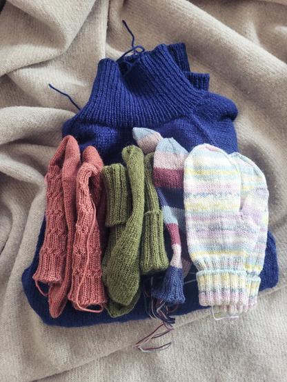 ENG A pile of knitting projects that with a lot of loose yarn ends showing. 

DEU Ein Stapel fast fertige Strickstücke, bei denen losen Fäden, die vernäht werden müssen raus schauen.