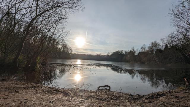 Winterlicher See, Eis auf dem Wasser, die Sonne steht tief.